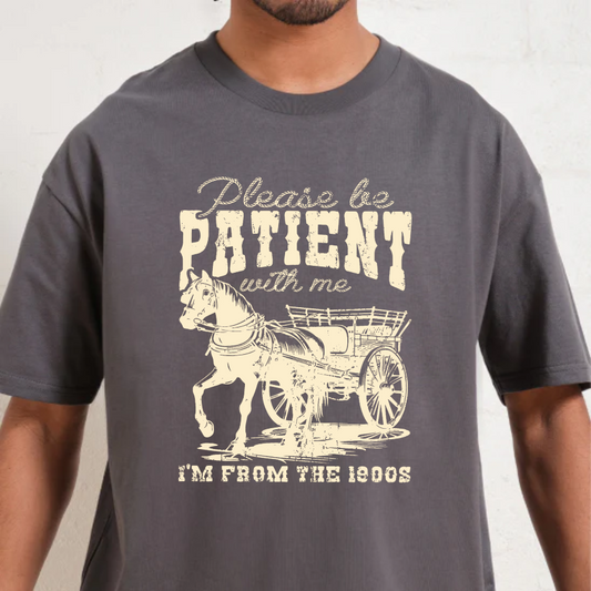 Charcoal t-shirt with a graphic of a horse and carriage and text 'Please be patient with me I'm from the 1800s' on a plain background.