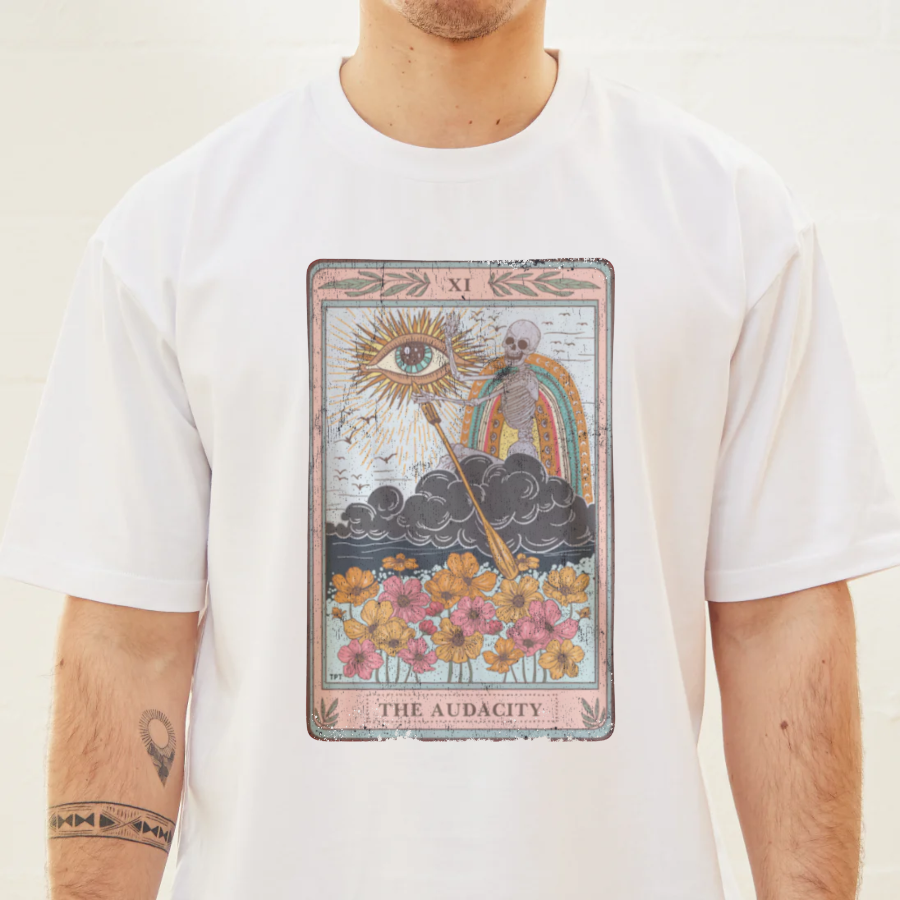 Person wearing a white t-shirt with a tarot card design featuring flowers and an eye.