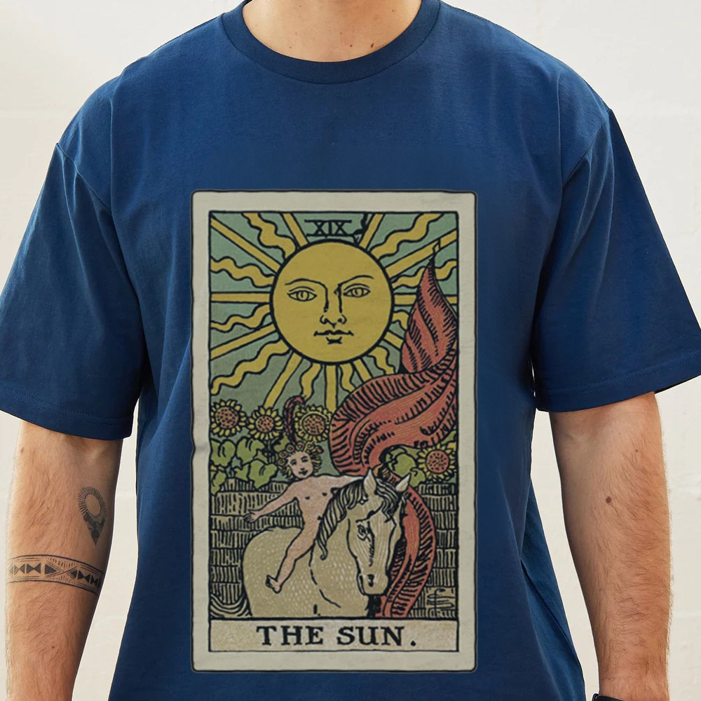 Person wearing a blue t-shirt with a tarot card design labeled 'The Sun'.