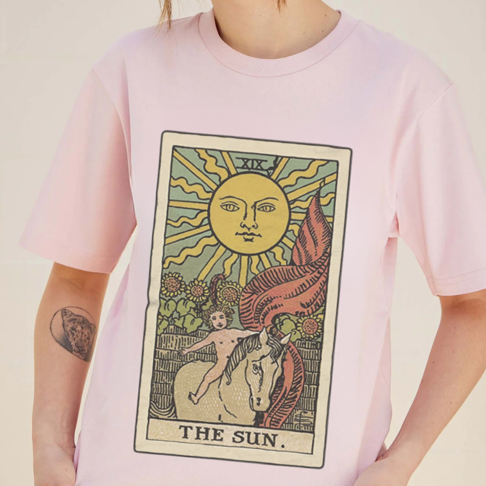 Person wearing a pink t-shirt with 'The Sun' tarot card design.