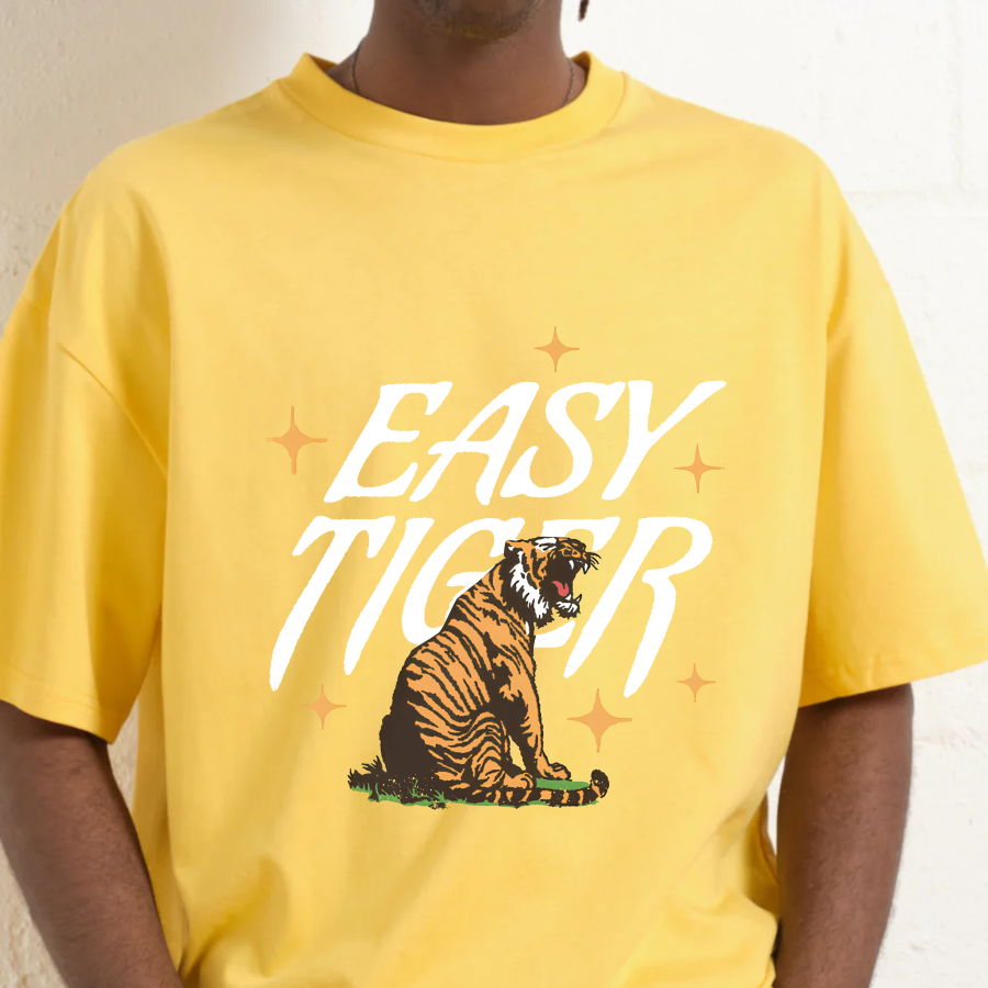 Yellow t-shirt with 'Easy Tiger' graphic design on a person against a neutral background