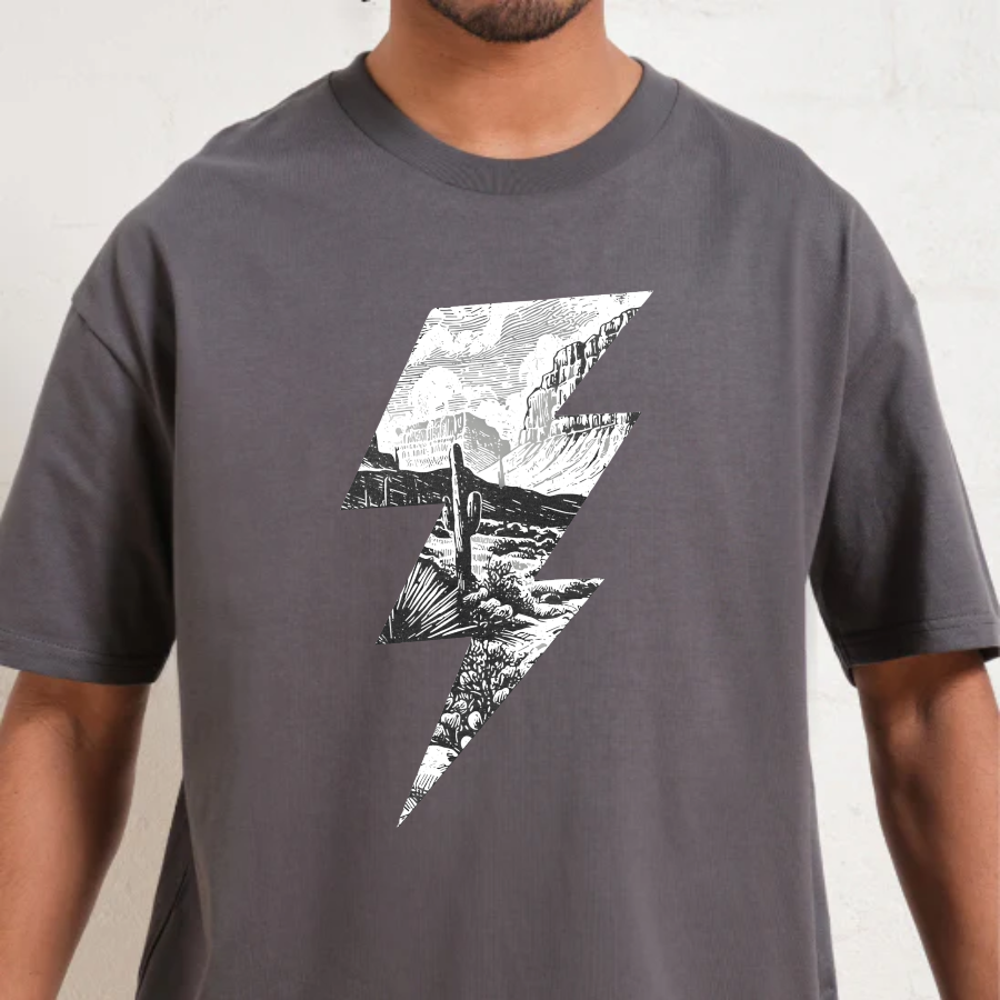 Person wearing a charcoal t-shirt with a black and white graphic design on a plain background