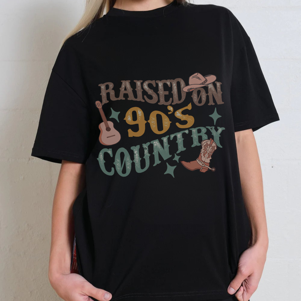 Black t-shirt with 'Raised on 90's Country' text and graphics worn by a person.