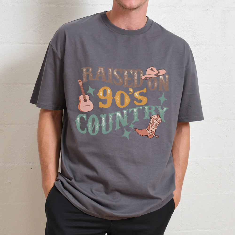 Person wearing a gray t-shirt with 'Raised on 90's Country' text and graphics.