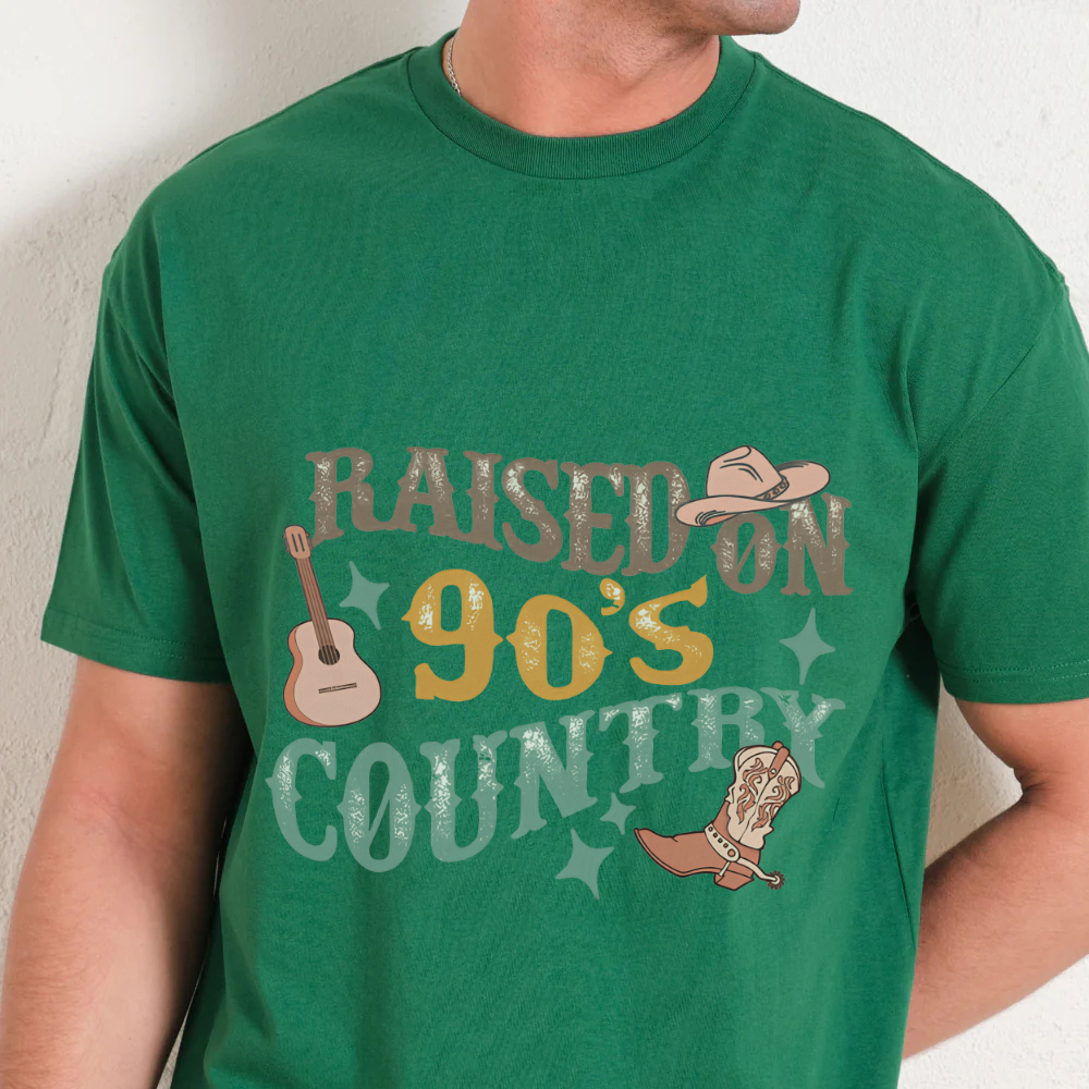 Green t-shirt with 'Raised on 90's Country' graphic design featuring a guitar, cowboy hat, and boot.
