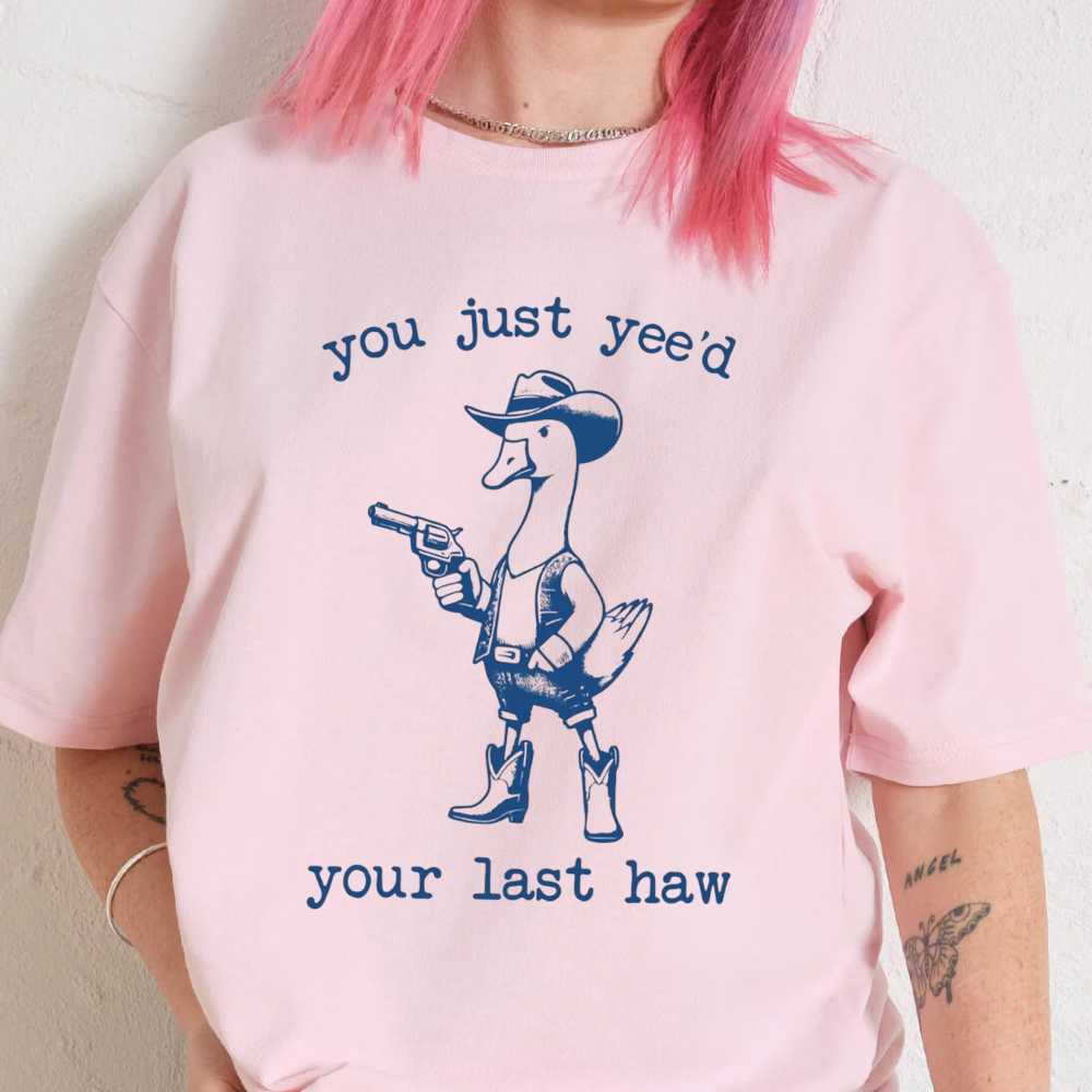 Person wearing a pink t-shirt with a graphic design and text.