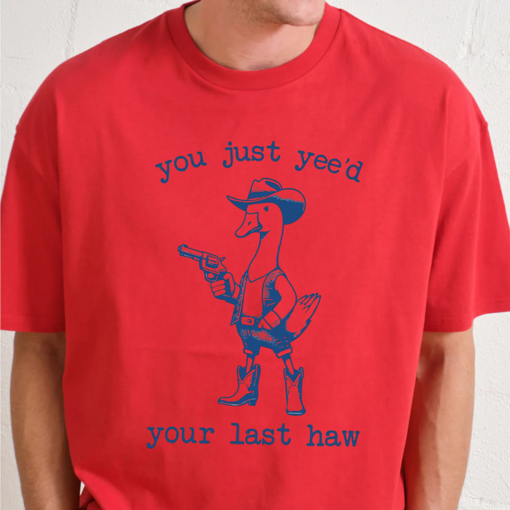 Red t-shirt with a graphic of a duck in a cowboy hat and boots, holding a gun, with text 'you just yee'd your last haw' on a white background.