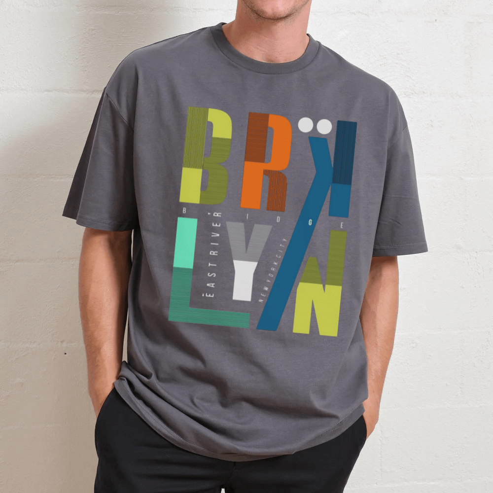 Person wearing a gray t-shirt with colorful 'BRKLYN' graphic design.