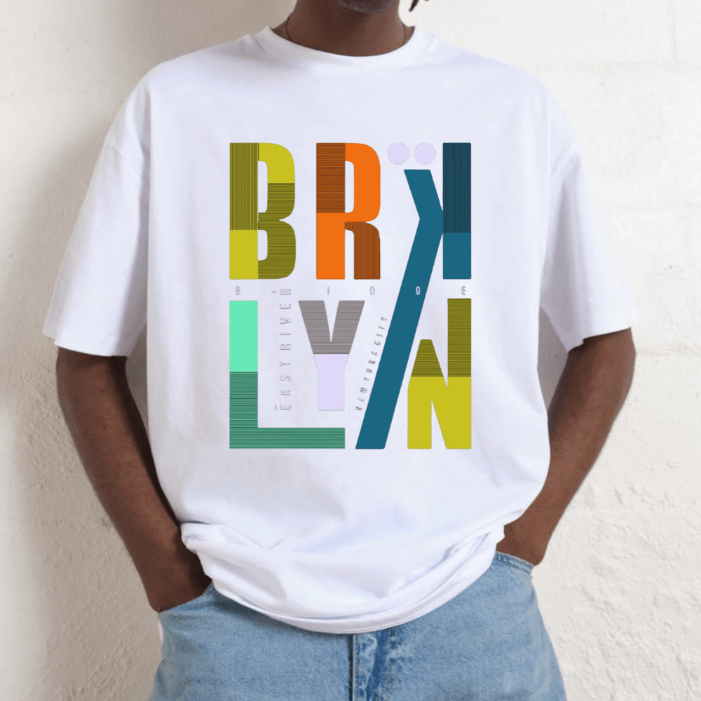 Person wearing a white t-shirt with colorful 'Brooklyn' graphic design.