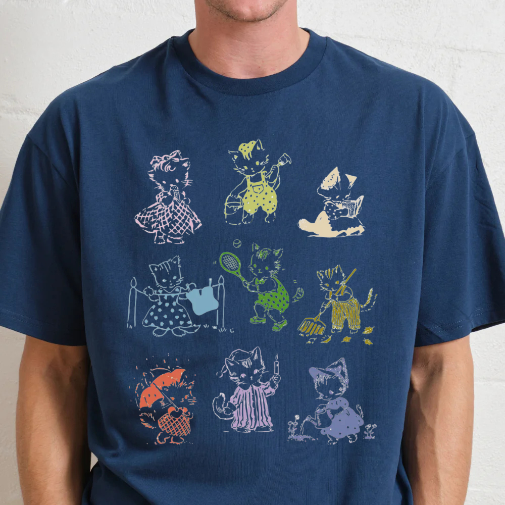 Navy blue t-shirt with colorful cat illustrations worn by a person against a light gray background