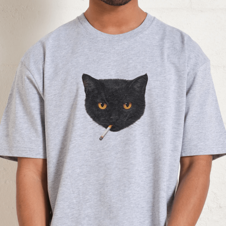 Person wearing a gray t-shirt with a black cat graphic holding a cigarette.