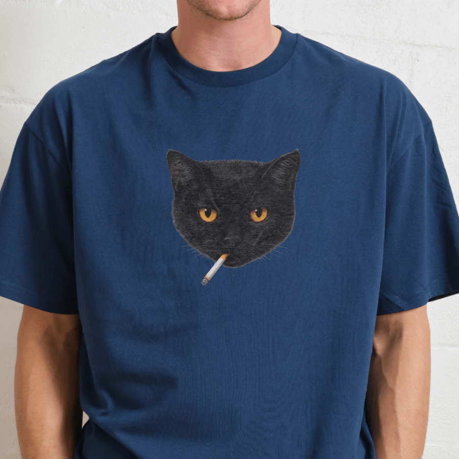Person wearing a blue t-shirt with a black cat graphic smoking a cigarette.