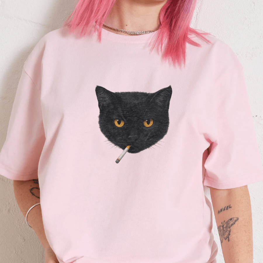 Person wearing a pink t-shirt with a black cat graphic holding a cigarette.