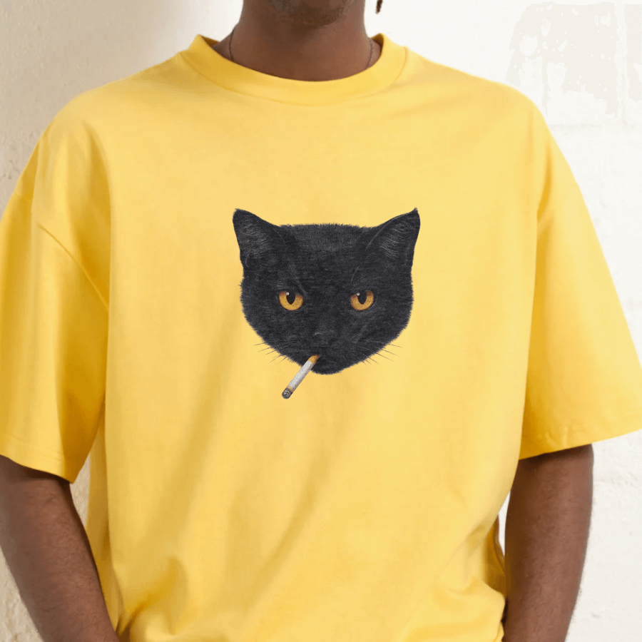Yellow t-shirt with a black cat graphic holding a cigarette on a neutral background