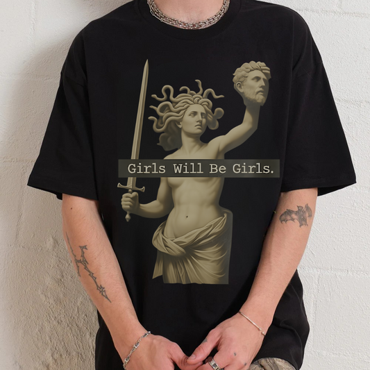 Black t-shirt with colorful cat illustrations worn by a person against a white wall.