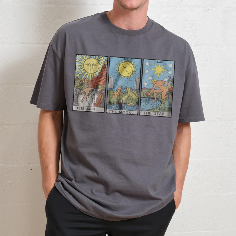 Person wearing a gray t-shirt with Tarot card designs on a plain background