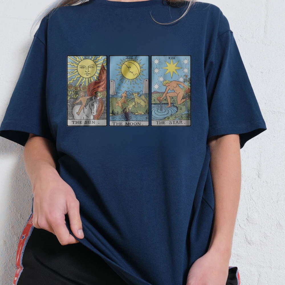 Navy blue t-shirt with tarot card designs worn by a person against a white wall.