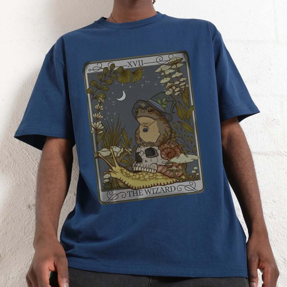 Person wearing a blue t-shirt with a graphic design of 'The Wizard' from a tarot card.