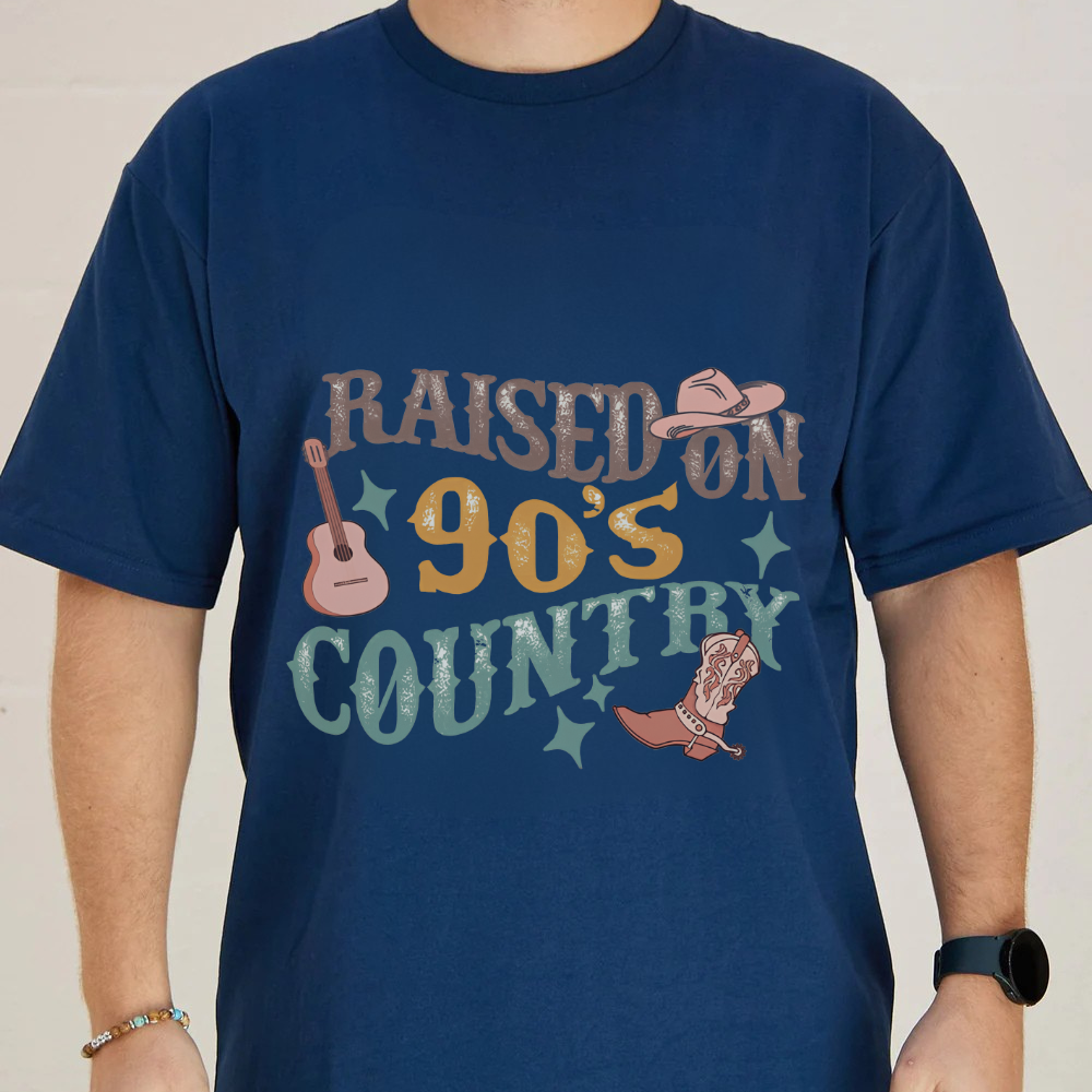 Navy blue t-shirt with 'Raised on 90's Country' graphic design featuring a guitar, cowboy hat, and boot.