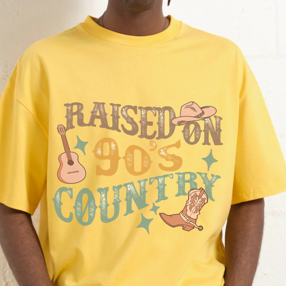 Yellow t-shirt with 'Raised on 90's Country' design featuring a guitar, cowboy hat, and boot.