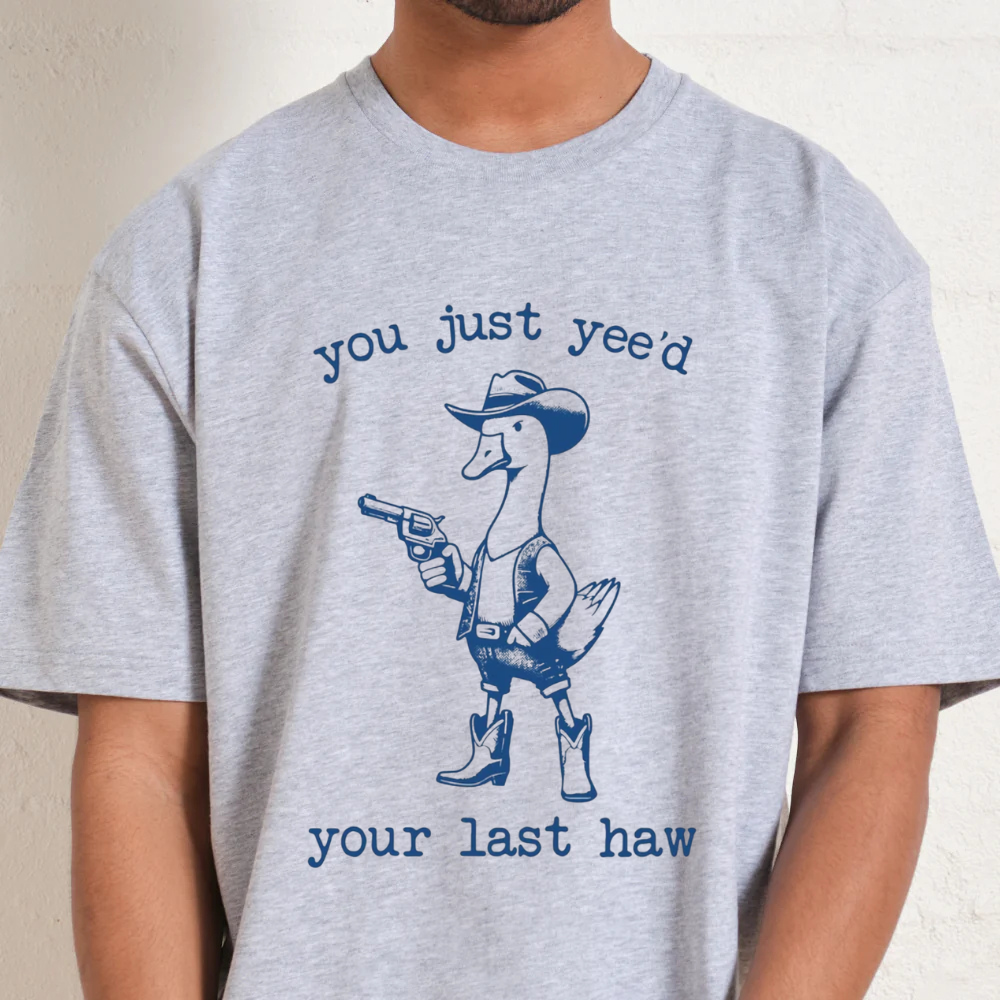Gray t-shirt with a graphic of a duck in a cowboy outfit and text on a plain background